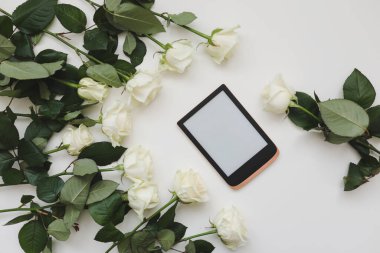 Beyaz güllerle süslenmiş zarif çiçek kompozisyonu ve beyaz arkaplanda yazı için yer