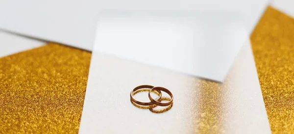 Dos anillos de boda dorados sobre un fondo dorado. Invitación de boda. regalo de San Valentín, venta de banner de compras plantilla, espacio para copiar — Foto de Stock