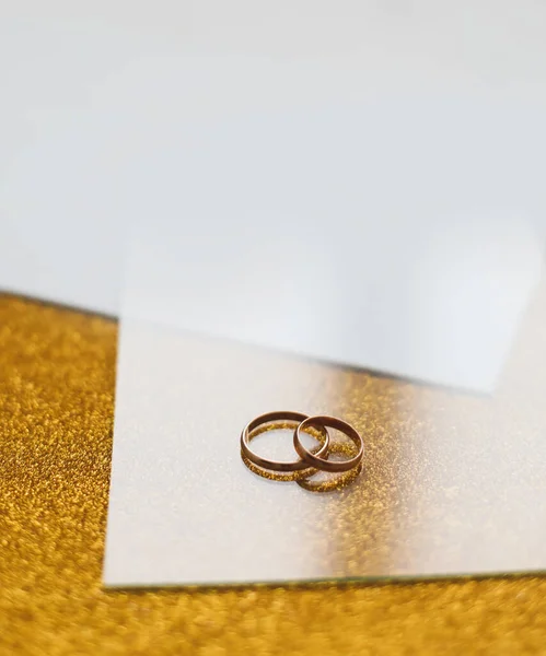 Dos anillos de boda dorados sobre un fondo dorado. Invitación de boda. regalo de San Valentín, venta de banner de compras plantilla, espacio para copiar — Foto de Stock