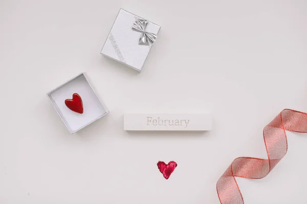 Шлюбна обручка і срібна ювелірна коробка на білому тлі з червоним серцем і червоною стрічкою. День шлюбу, ювілею, заручин або Валентинів. З днем.. — стокове фото