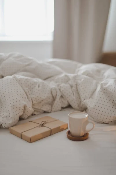 Bir fincan kahve ve beyaz çarşaflı ve battaniyeli bir hediye. Yatak konseptinde sabah kahvesi. — Stok fotoğraf