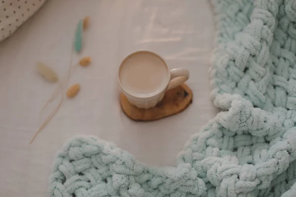 Taza de café con leche en la cama con sábanas blancas y manta. Café de la mañana en concepto de cama. —  Fotos de Stock