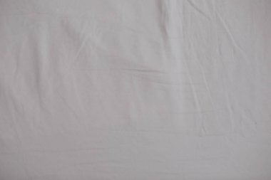 Kumaş doku arka plan. Buruşuk, buruşuk kumaş. Gece uykusundan sonra dağınık bir yatak çarşafı üst görünümü. Gece uykusundan sonra yatak odasında yapılmamış çarşaf. Yakın çekim tekstil arka plan. Yumuşak odaklama