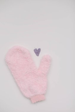 Eldivenli masaj bezi ve beyaz arka planda menekşe tozundan yapılmış bir kalp. Sıfır atık kavramı