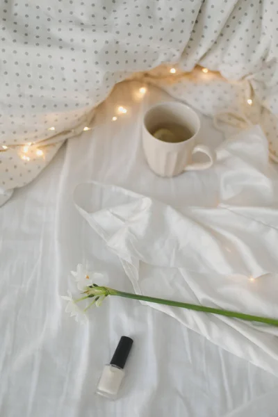 Tazza di tè al limone, narciso e accessori sul letto. Colazione a letto. Buongiorno. Primavera. — Foto Stock