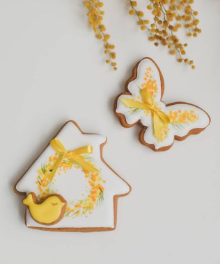 Beyaz arka planda Paskalya zencefilli kurabiye ve sarı mimoza çiçekleri.