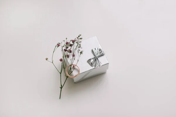 Caja con anillo de compromiso dorado sobre fondo de flores, vista superior. Boda, concepto de propuesta de matrimonio — Foto de Stock