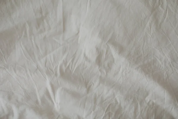 Fabric texture background. Wrinkled, crumpled fabric. Top view of a messy bedding sheet after night sleep. Unmade bed sheet in the bedroom after night sleep. Closeup textile background. Soft focus — Stock Photo, Image