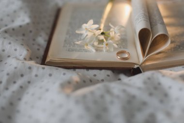 Altın yüzük ve yatakta kalp şeklinde katlanmış çarşafları olan açık bir kitap. Düğün konsepti, Sevgililer Günün kutlu olsun.