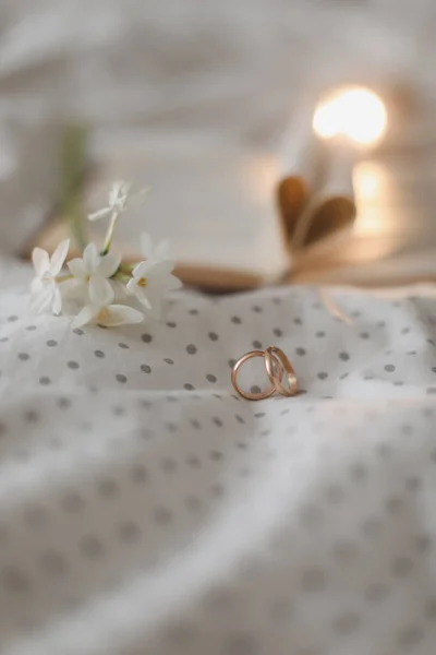 Boda anillo de oro y libro abierto con sábanas plegadas en forma de corazón en la cama. Concepto de boda, Feliz día de San Valentín — Foto de Stock