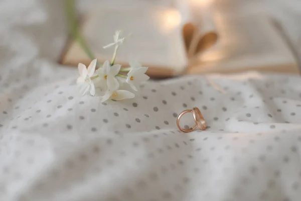 Bague dorée et livre ouvert avec draps pliés en forme de coeur au lit. Concept de mariage, Joyeuse Saint Valentin — Photo