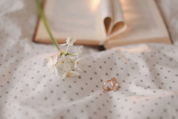 Svatební zlatý prsten a otevřená kniha se složenými prostěradly ve tvaru srdce v posteli. Svatební koncept, Šťastný Valentýn — Stock fotografie
