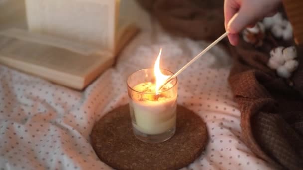 Уютный натюрморт с книгой, горящей свечой и хлопковой веточкой в теплой мягкой постели. Милый дом. Full HD видео — стоковое видео