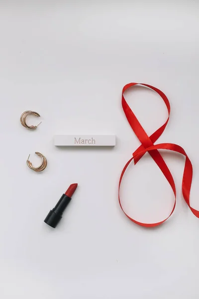 Ocho de ribbom rojo, lápiz labial y accesorios planas vista superior. Concepto Día de la Mujer, 8 de marzo — Foto de Stock