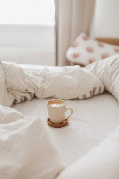 Sabahları kahve fincanı ve yatakta kahvaltıyla rahat bir yatağı var. — Stok fotoğraf