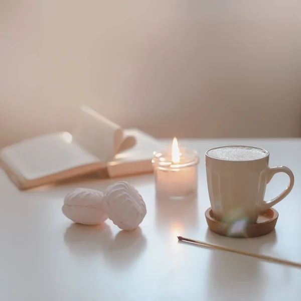 Nature morte confortable avec une tasse de café, bougie, livre ouvert sur un fond ensoleillé. Printemps décor intérieur de la maison. Bonjour. — Photo