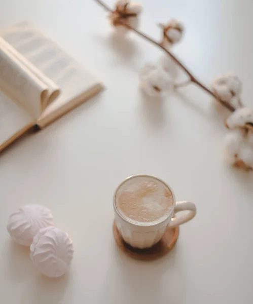 Xícara de café, flor de algodão, livro aberto em uma mesa branca vista superior de fundo — Fotografia de Stock