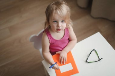 Masanın üstünde bir deftere yazı yazan komik bir kız.