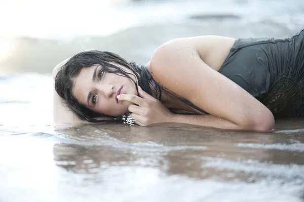 Kvinnlig modell i en våt klänning på stranden — Stockfoto
