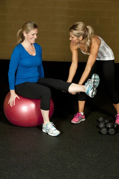 Gravid kvinna stretching med kvinnliga tränare — Stockfoto