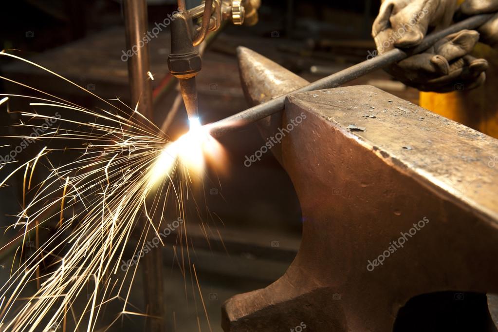 Metal fabricator utilizing a torch to heat up a piece of metal — Stock