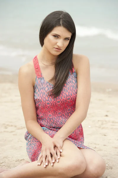 Kvinnlig modell sitter på stranden — Stockfoto