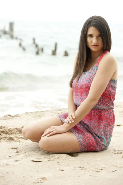 Modelo femenino sentado en la playa — Foto de Stock