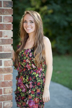 Esmer kız bir tuğla duvara yakın poz