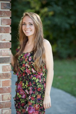 Esmer kız bir tuğla duvara yakın poz