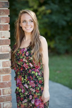 Esmer kız bir tuğla duvara yakın poz