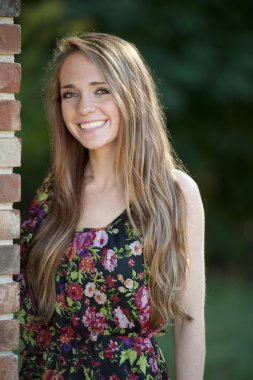 Esmer kız bir tuğla duvara yakın poz