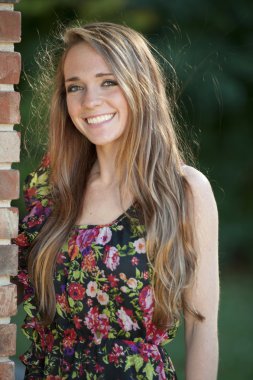 Esmer kız bir tuğla duvara yakın poz