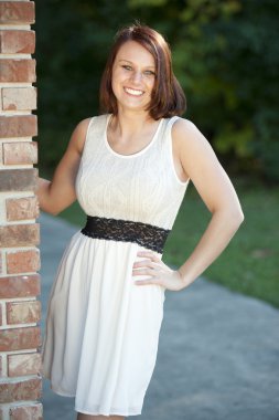 Esmer kız bir tuğla duvara yakın poz