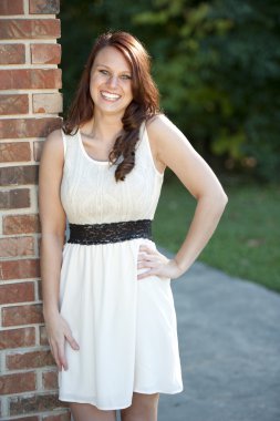 Genç esmer bir tuğla duvara yakın poz