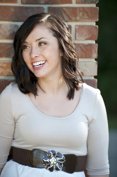 Brunette fille posant près d'un mur de briques — Photo