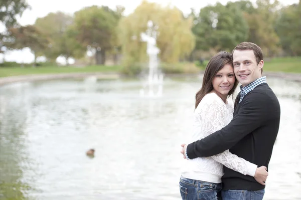 Jovem casal posando ao lado da lagoa — Fotografia de Stock