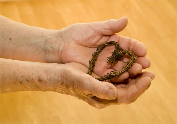 Hands of old woman and the heart — Stock Photo, Image