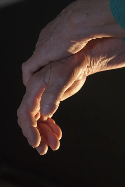 Hand van oude vrouw in het ligh van lamp — Stockfoto