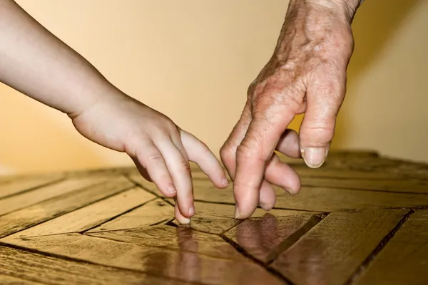 Handen van oude vrouw en kind in het spel — Stockfoto