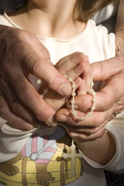 Händerna på gammal kvinna på bön med barnbarnet — Stockfoto