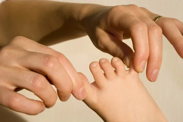 Hand van moeder en voeten van baby — Stockfoto