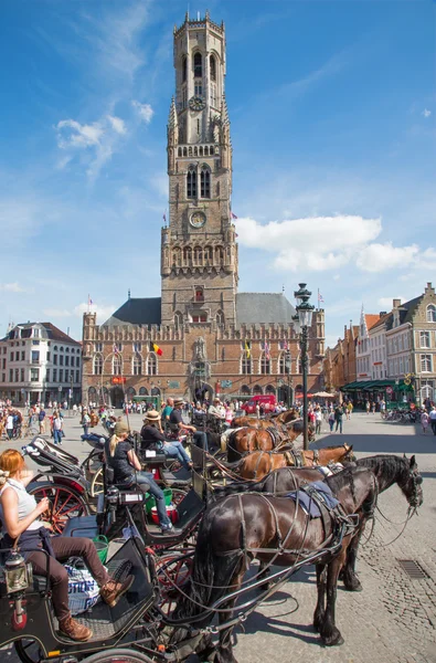 BRUGES, BELGIUM - JUNE 12, 2014: The Carriage on the Grote Markt and Belfort van Brugge in background. — Stock Photo, Image