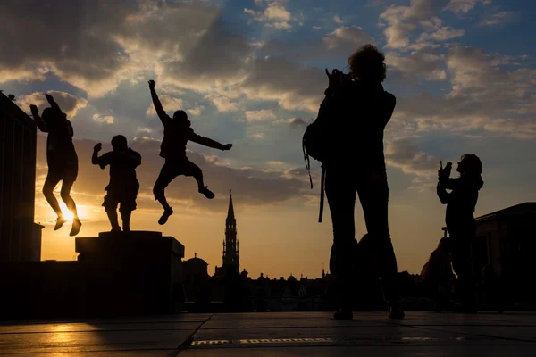 Brüsszel, Belgium - június 14-én 2014: Silhouette ugrott fiúk este Monts des Arts a város fölött. — Stock Fotó