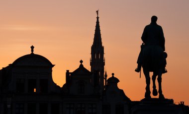 Brüksel - Kral Albert heykelinin silueti ve Monts des Arts 'tan akşamları belediye binasının kulesi