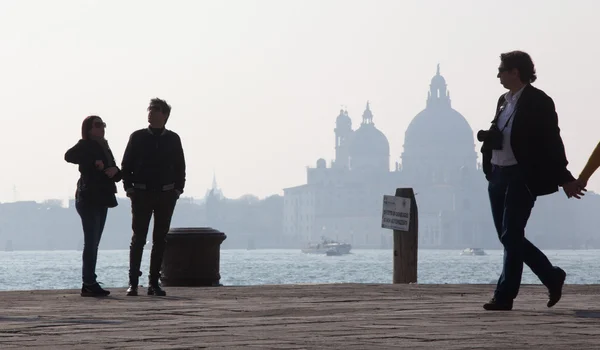 VENICE, ITÁLIA - MARÇO 14, 2014: Caminhando à beira-mar e silhueta da igreja de Santa Maria della Salute . — Fotografia de Stock