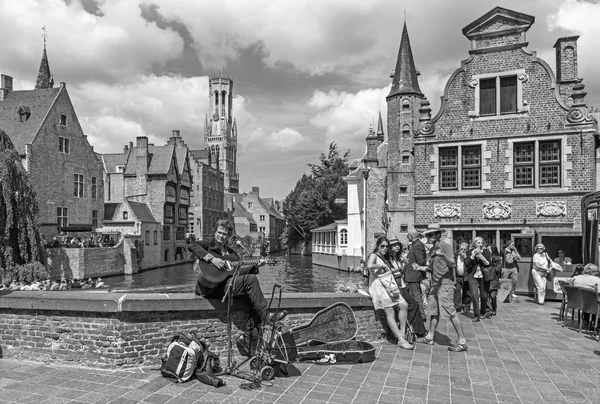 Brugge - uitzicht vanaf de rozenhoedkaai in brugge met de straat muzikant en het perez de malvenda huis en belfort van brugge in de achtergrond. — Stockfoto