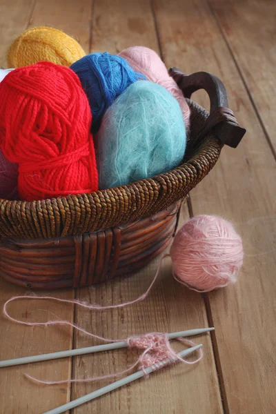 Fios coloridos e agulhas de tricô em uma mesa de madeira — Fotografia de Stock