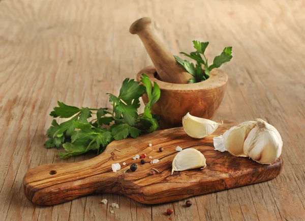 Knoblauch, Petersilie und Gewürze auf einem Kochbrett — Stockfoto