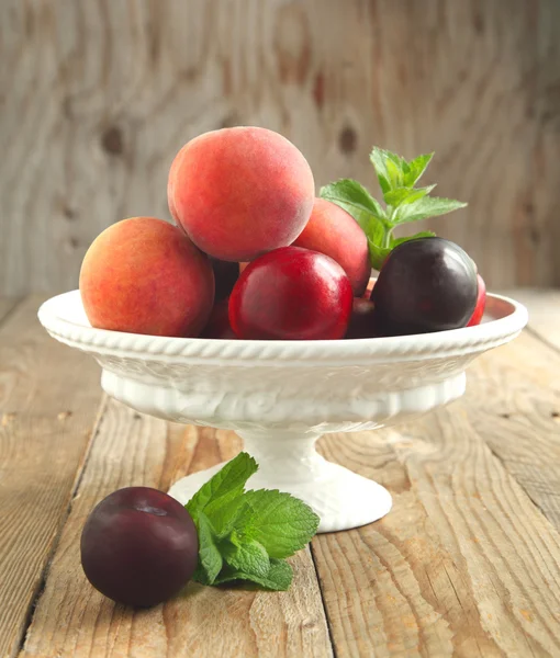 Färska persikor, nektariner och plommon i vas — Stockfoto