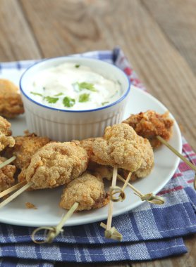 Fried cornmeal-crusted chicken bites with yogurt herb dressing clipart